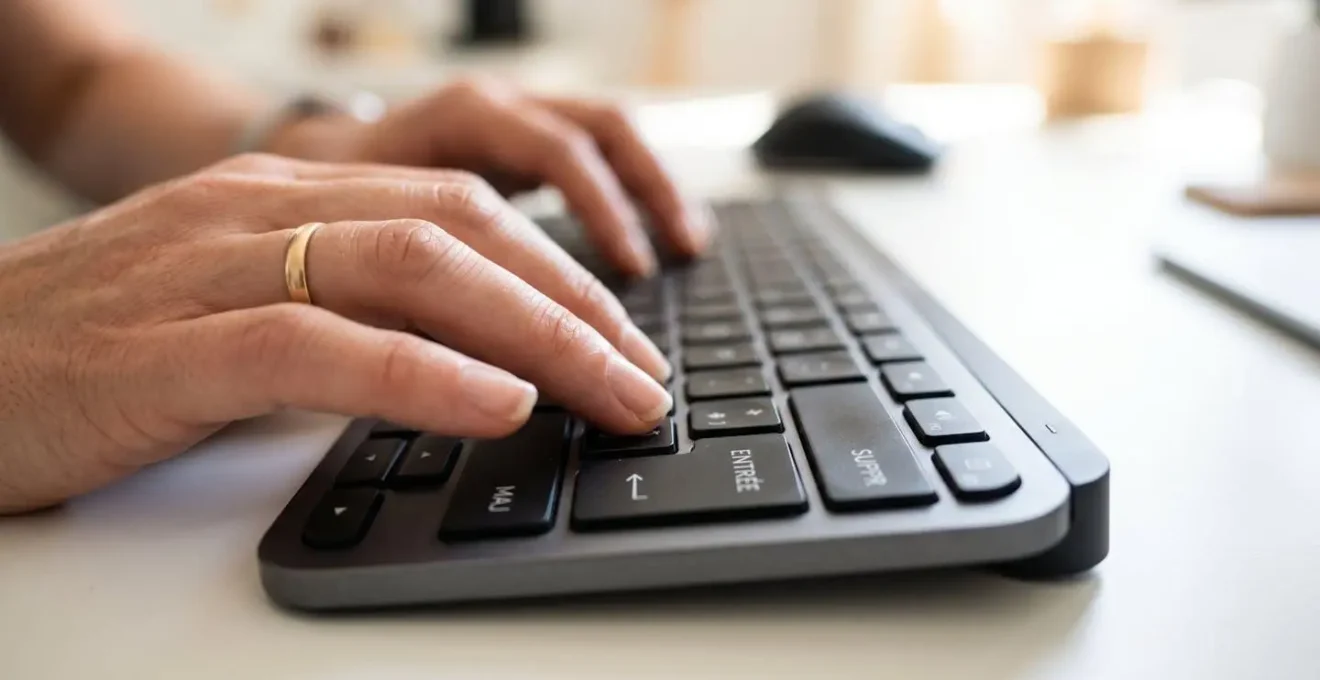 Gros plan sur des mains en train de taper sur un clavier d'ordinateur moderne, mise au point nette sur les touches